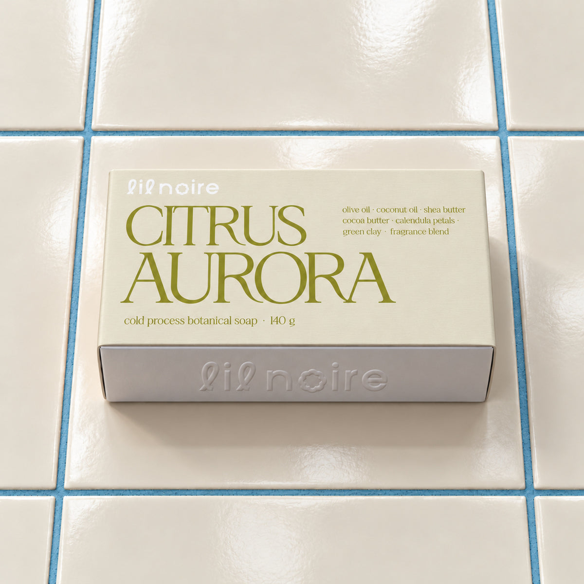 Citrus Aurora 140 g botanik sabun, kapalı kutu; krem fayans ve mavi derz üzerinde