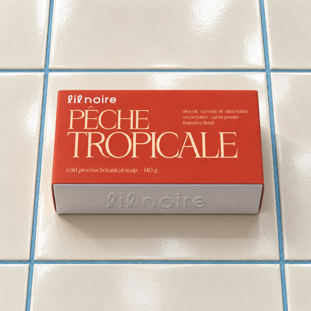 Pêche Tropicale 140 g botanik sabun, kapalı kutu; krem fayans ve mavi derz üzerinde