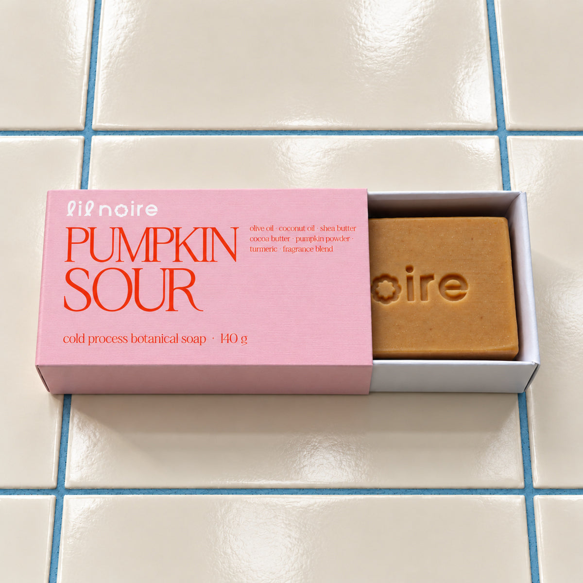 Pumpkin Sour 140 g botanik sabun, açık çekmeceli kutu; krem fayans ve mavi derz üzerinde